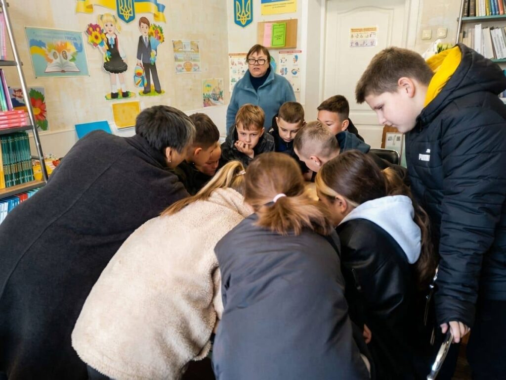 Група учнів Кременчуцького ліцею 11 бере участь у бібліотечному заході, уважно слухаючи та обговорюючи завдання.