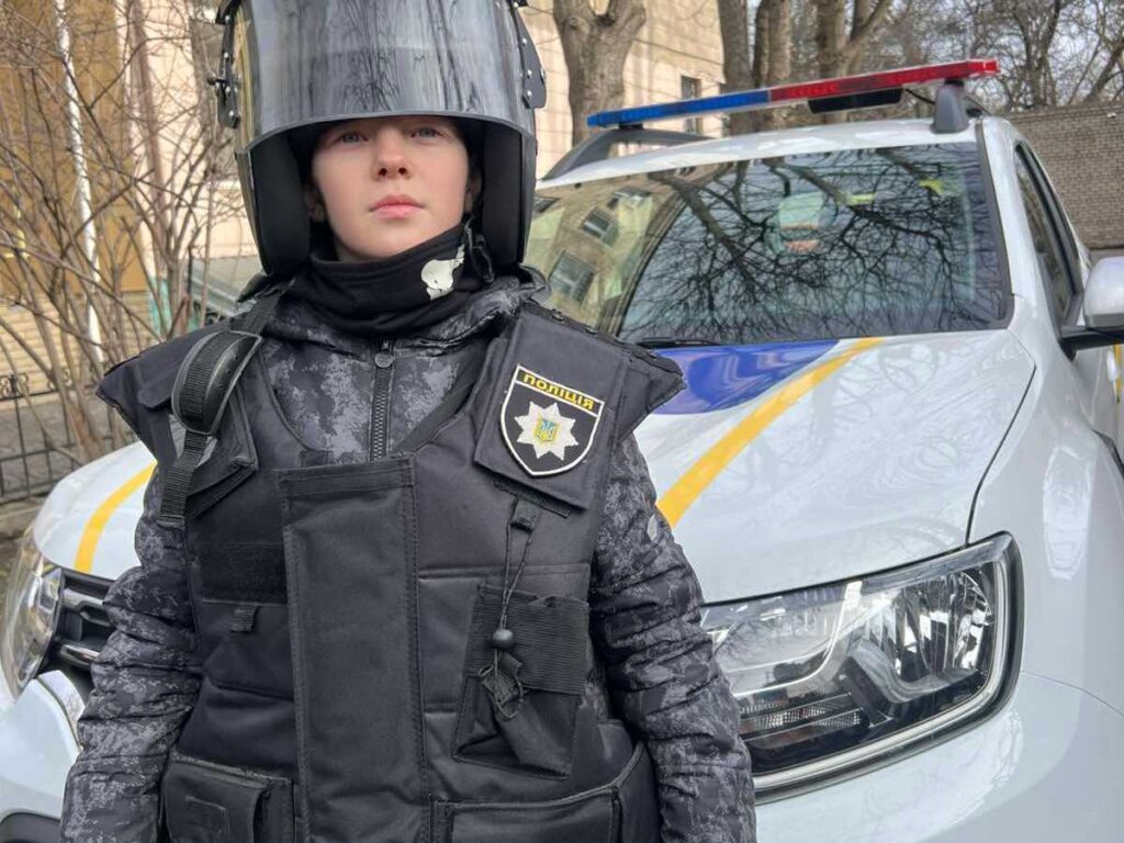 Учень 11 ліцею в захисному спорядженні перед патрульним авто