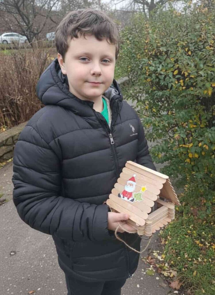 Учень Кременчуцького ліцею 11 тримає дерев'яну годівничку для птахів