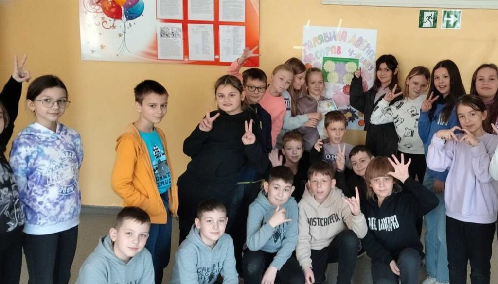 Групове фото учнів початкової школи біля інформаційного стенду «Галявина добрих справ»