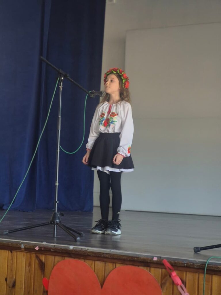 Дівчинка у віночку декламує вірш на Шевченківські читання у ліцеї
