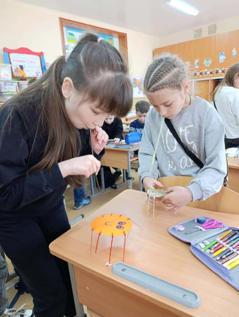 Дівчата проводять експеримент з рухом павучків за допомогою повітря